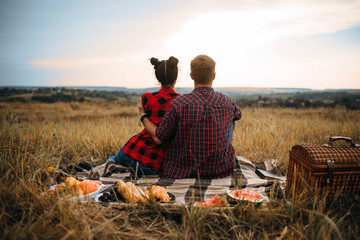 Love couple sitting on plaid, back view