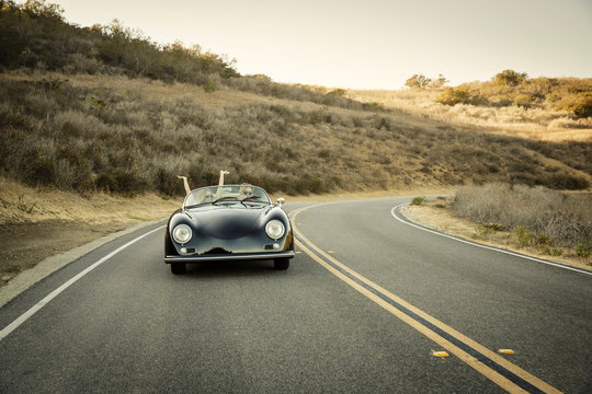 Young couple drive convertible uphill