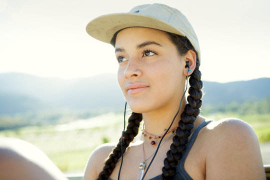 Young woman wears baseball cap and headphones