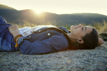 Young woman in jean jacket relaxes on gravel