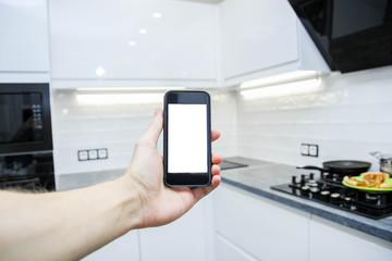 Smart home system. Smartphone with a white screen on the background of the kitchen.