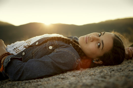 Young woman relaxes by mountains at sunset