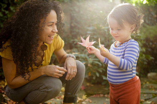 Mother and toddler look at autumn leaves