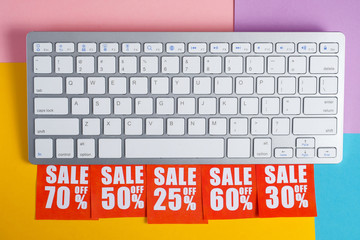 Online shopping discount concept. Red labels with percents under the white keyboard on a...