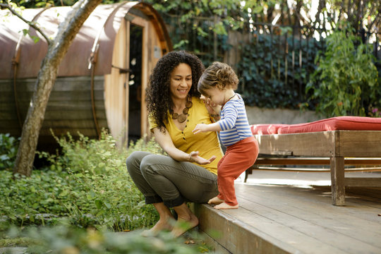 Mother helps toddler step off deck