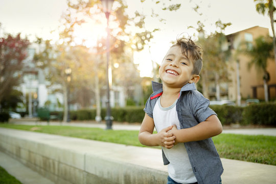 Young boy with mohawk grins while standing outdoors
