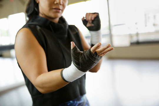Woman boxer looks at hand wraps in gym