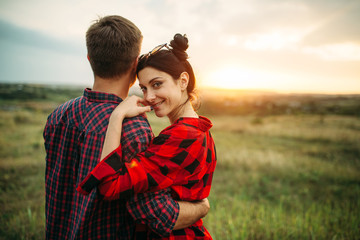 Happy love couple hugs in summer field at sunset