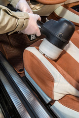 Obraz premium Close up of cheerful car repair shop worker is cleaning the interior of the car. He is holding a vacuum cleaner and touching it to the seat. The man is smiling