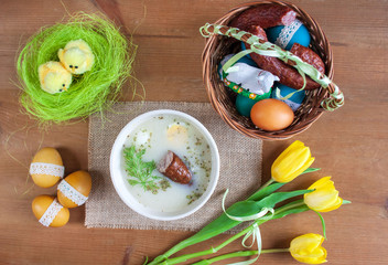 Śniadanie wielkanocne - żurek z jajkiemi i kiełbasą, obok pisanki, koszyczek ze świeconką © Monika