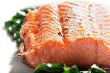 A piece of steamed salmon steak with spinach