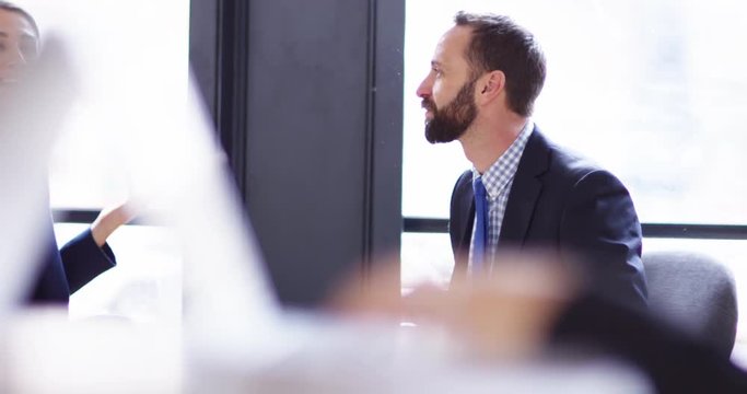 4K Smiling business man & woman talking in sunlit office with soft focus foreground