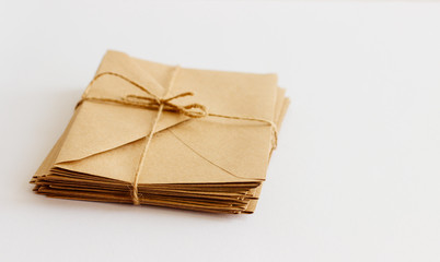 Mail kraft envelopes on white background, closeup. A stack of letters wrapped in twine.