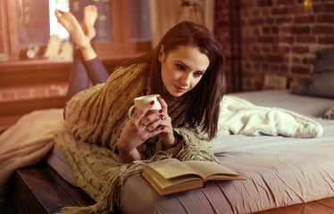 Portrait of a brunette lady reading a book in a winter evening