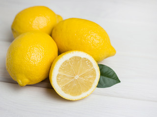 Whole and sliced lemons on white wooden background. Organic fresh citrus fruits, top view, copy space.