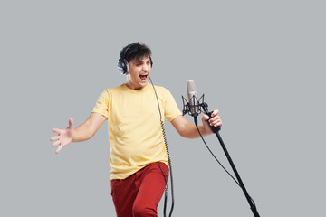 Portrait of rock singer man in studio professional headphones keeping static acoustic mic, sings a...