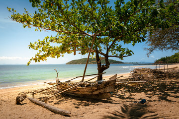 old wooden fishing boat on a beach with a beautiful tropical seascape on the background. wooden african piroga, madagasar