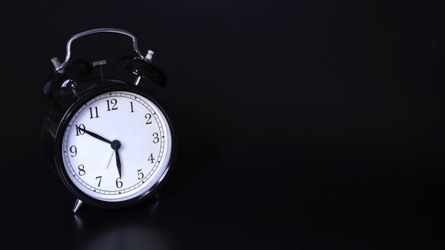 Close up image of old black vintage alarm clock. 10 minutes before six o'clock