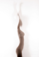 Silhouette of woman dancing behind a glass door