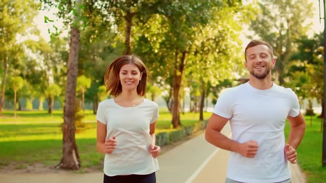 happy young couple jogging in the park.smiling caucasian man and woman wears sportswear enjoy working out at summer morning