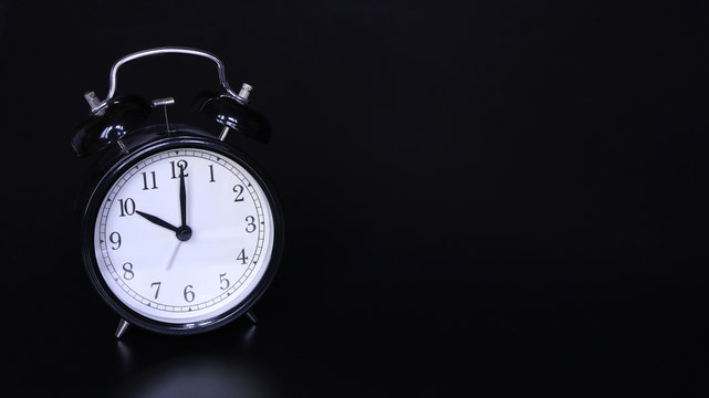 Close up image of old black vintage alarm clock. Ten o'clock