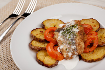 Baked potatoes in the peel sliced with tomato and grilled meat in a white sauce.