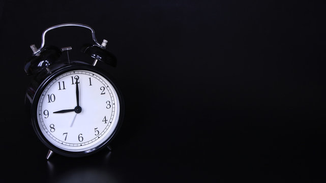 Close up image of old black vintage alarm clock. Nine o'clock