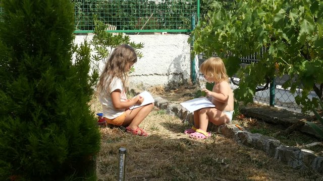 Children playing in the yard. Two kids sitting and playing with note books