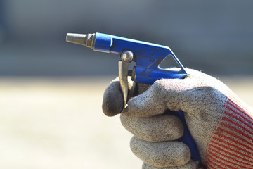 Compressed air gun in the hand of a worker. - obrazy, fototapety, plakaty