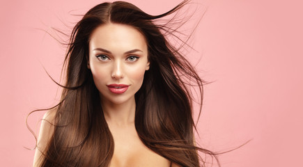 Volume Brown hair model face portrait. Elegant attractive woman with perfect skin and natural make up against pink background. Beauty salon and cosmetics concept. Banner with copy space.