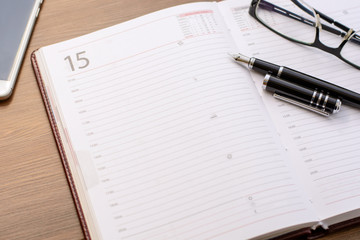 Men's business accessories - a black leather notepad, fountain pen on the office desk. Business and education.