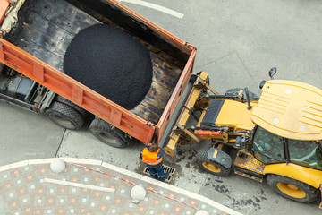 Heavy industrial dump truck unloading hot asphalt .City road construction and renewal site © Kyryl Gorlov