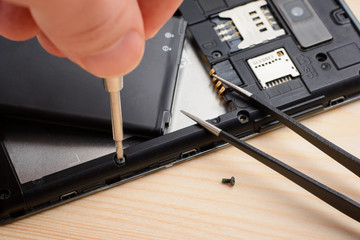 Technician repair mobile phone with a help of screwdriver