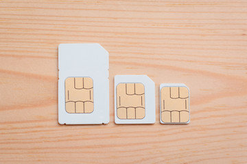 SIM cards of different side on a wooden background. SIM card, micro SIM and nano SIM on table