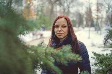 Naklejka premium Girl walking in the fresh air in winter. Cheerful and beautiful woman posing on the street, in the city Park. Concept: a walk in the fresh air, the guarantee of health and good mood