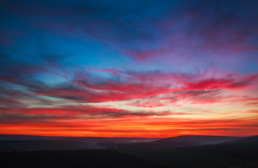 Colorful magnificent sunset in countryside above hills and fields, beauty nature background