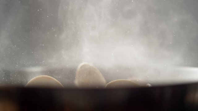Camera follows cooking clams in a pan. Shot with high speed camera, phantom flex 4K. Slow Motion.