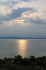 The sun breaking through the clouds over lake Garda Italy