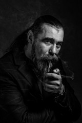 Portrait of a man with a beard the smoking a pipe.Pipe smoking vintage characteristic senior man with gray hair and beard. dark background.