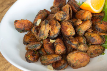 Breaded mussels with dill and garlic, garnished with lettuce leaf and slice of lemon. Closeup.