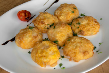 Breaded balls. With white and yellow cheese, flour, egg. Garnished with cherry tomatoes, parsley and balsamic dressing. Closeup.
