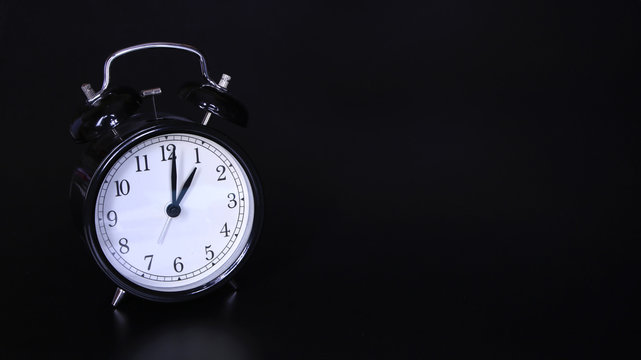 Close up image of old black vintage alarm clock. One o'clock