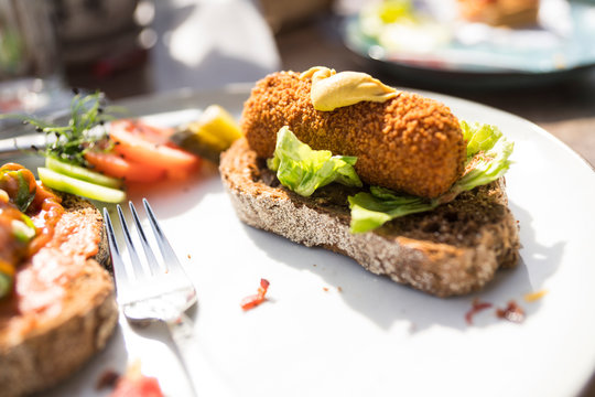 plate with typical meal, fired snack croquet with salad on slice of bread