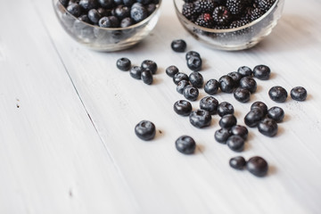 Plates with blueberry and blackberry on a wooden table top view.
