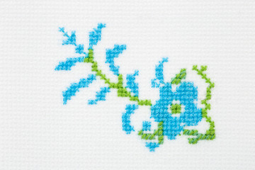 Forget-me-not flower embroidered with a cross on textile canvas