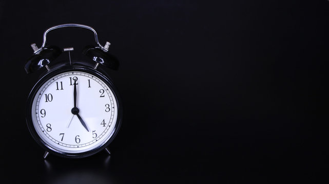 Close up image of old black vintage alarm clock. Five o'clock