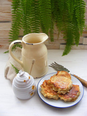 vertical photo of fritters pancakes with oak flakes on shabby wooden white background with rustic jug