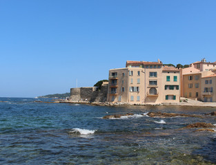 La Ponche Saint-Tropez beach. Blue sky, clear water of the Mediterranean Sea and the stone wall of the historic fortress.