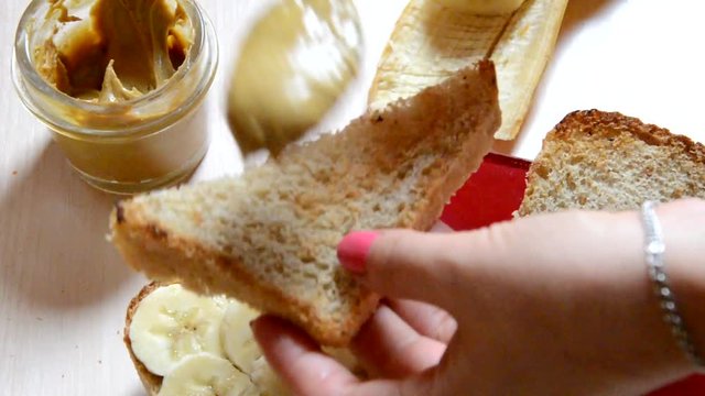 girl woman makes Homemade peanut butter and bananas for healthy breakfast or picnic. Homemade peanut butter ingredients: peanuts (roasted, unsalted, shelled), peanut oil, honey. No salt, no sugar.