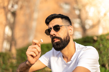 Hipster Guy Sitting Outdoors Holding a Flower.